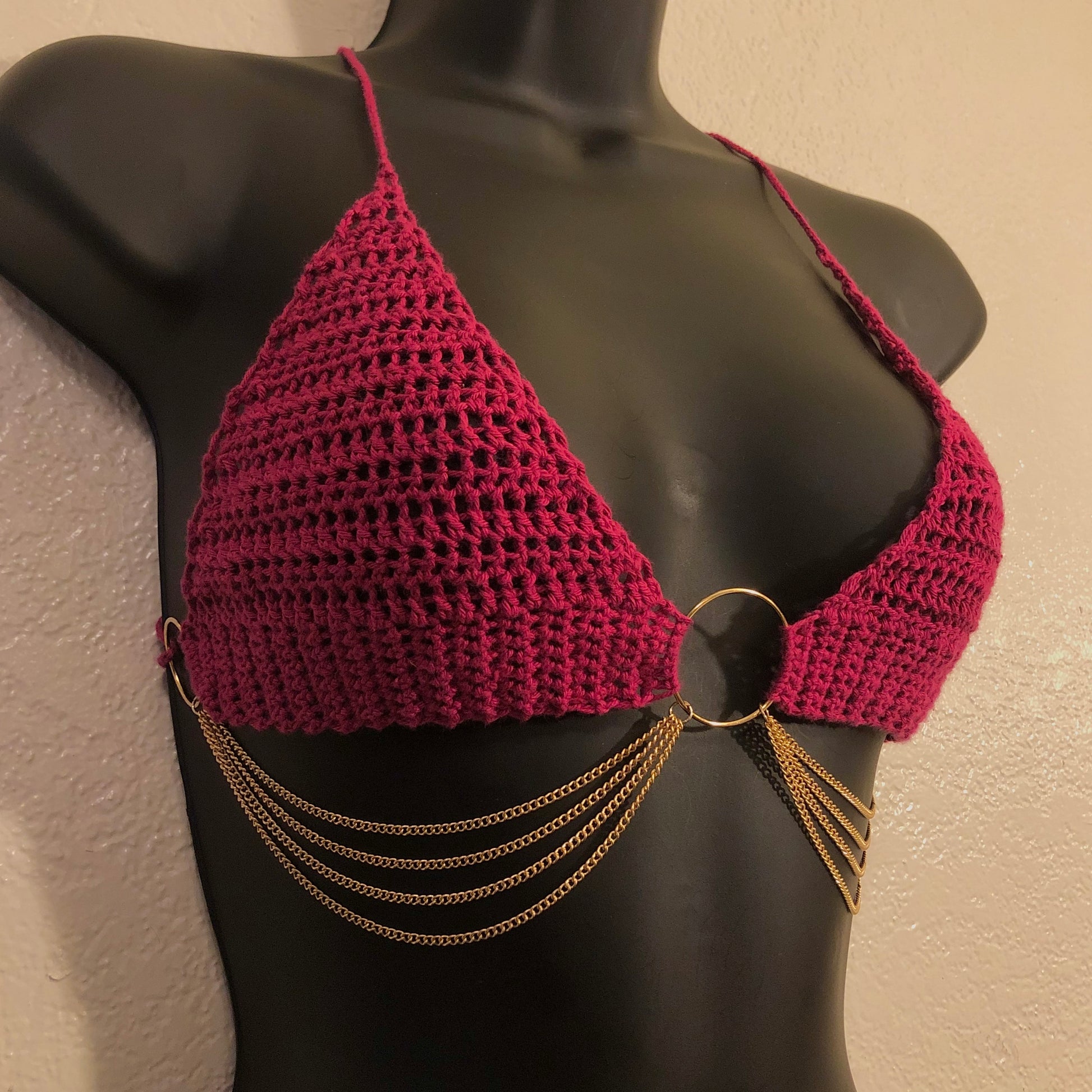 Crocheted halter top made with a lightweight cotton yarn in the color raspberry. Embellished with nickel-free gold colored rings and chains. 